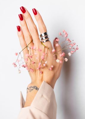 soft-gentle-photo-woman-hand-with-big-ring-red-manicure-hold-cute-little-pink-dried-flowers-white